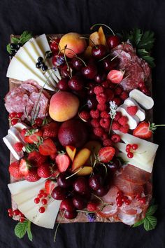 an assortment of cheeses, fruits and meats on a platter