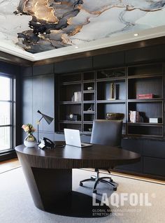 an office with a desk and bookcases on the wall, along with a large window