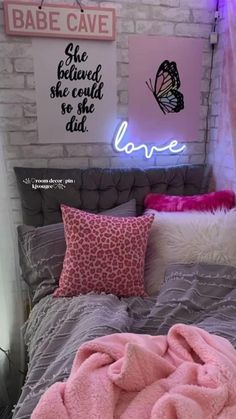 a bed with pink blankets and pillows on it in a room that has brick walls