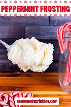 a spoon full of peppermint frosting with candy canes in the background