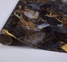 a piece of black marble with gold foil on it