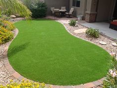 a backyard with green grass and flowers around it