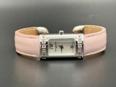 This vintage Saint Honore Paris watch features a Swiss-made quartz movement housed in a sleek rectangular case. The watch is adorned with pink rhinestones around the dial and complemented by a pink leather strap, adding a touch of elegance. The mother-of-pearl dial is slightly cracked but does not affect the watch's functionality, enhancing its vintage charm. The compact case size makes it perfect for a dainty wrist, fitting up to 16 cm, offering both style and comfort. This piece is ideal for collectors or anyone looking to add a sophisticated accessory to their wardrobe. --Please Read-- All sales are final except for damages in shipping or quality issues. Please feel free to ask questions before purchase. Offers are always welcomed and we offer discounts for repeating customers. All inte Elegant Pink Rectangular Watch, Elegant Pink Rectangular Watches, Women Wrist Watch, Pink Rhinestones, Pink Leather, Quartz Watch, Quartz Movement, Vintage Charms, Mother Of Pearl