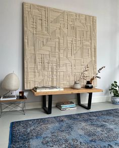 a table with some books on top of it next to a rug and potted plants