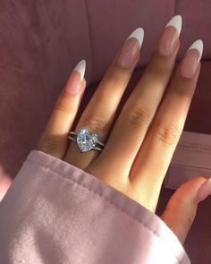 a woman's hand with white nails and a diamond ring on her left hand