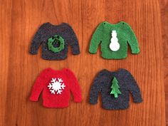 three knitted sweaters with snowflakes and trees on them sitting on a wooden surface