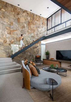 a living room filled with furniture next to a stone wall and stairs leading up to the second floor