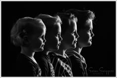 black and white photograph of three young boys with their heads turned to the side in profile