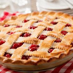 a cherry pie sitting on top of a red and white checkered table cloth