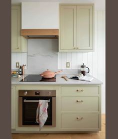 a kitchen with green cabinets and an oven