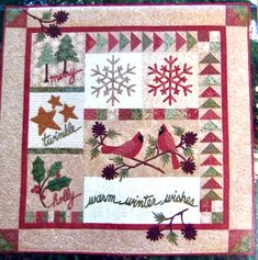 a quilted wall hanging on the side of a tree with snowflakes and birds