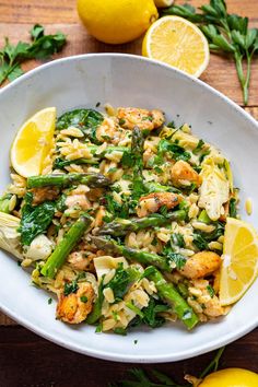 a white bowl filled with pasta and asparagus on top of a wooden table