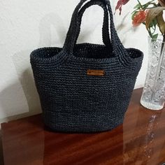 Hand knitted from 2 layers of yarn with a floss raffia mixture. It was knitted using the single needle method. The handle is knitted together with the bag. There is careful workmanship. It can accompany both your sports and stylish clothes. It is comfortable to use. Thanks to its large volume, you can carry many of your belongings in it. It is lightweight and very useful. In addition to using it when going to an evening party, you can also use it comfortably in your daily life. Its height is 28 cm and base width is 36 cm. Casual Handmade Black Straw Bag, Casual Black Handmade Straw Bag, Eco-friendly Black Crochet Bag With Braided Handles, Casual Hand Knitted Rectangular Straw Bag, Casual Hand-knitted Rectangular Straw Bag, Casual Rectangular Hand Knitted Straw Bag, Casual Black Handwoven Straw Bag, Eco-friendly Black Crochet Woven Bag, Casual Crochet Straw Bag Made Of Yarn