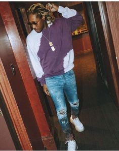 a man with dreadlocks standing in an open doorway wearing a purple and white shirt