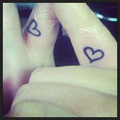 two fingers with hearts tattooed on them