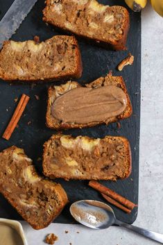 slices of banana bread with peanut butter and cinnamon on top, next to two spoons