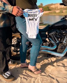 a man and woman standing next to each other holding up a motorcycle t - shirt