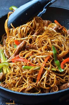 stir fry noodles with beef and peppers in a skillet on a table top, ready to be eaten