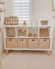 a white shelf filled with lots of storage bins next to a wall mounted clock