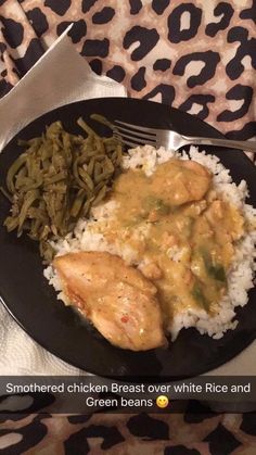 chicken breast over white rice and green beans on black plate with leopard print tablecloth