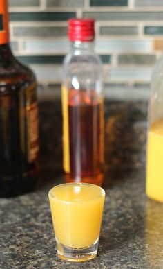 a shot glass filled with liquid sitting on top of a counter next to two bottles