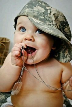 a baby wearing a camo hat and holding a chain