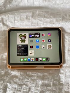 an ipad sitting on top of a white bed covered in sheets and pillows with icons