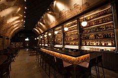 a dimly lit bar with lots of bottles on the shelves and lights hanging from the ceiling