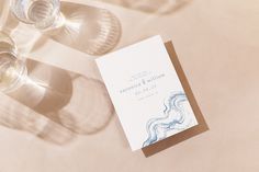 a table topped with wine glasses and a wedding program on top of a white table cloth