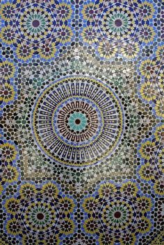 an intricately designed wall in the middle of a room with blue, green and yellow tiles