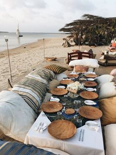 a table set up on the beach with plates and bowls laid out in front of it