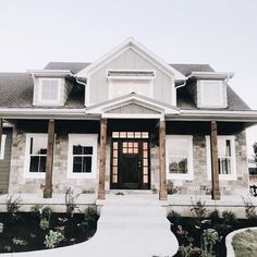 a house that has snow on the ground in front of it and two large windows