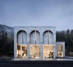 the building is made out of concrete and has arched doorways on both sides, leading to an outdoor dining area