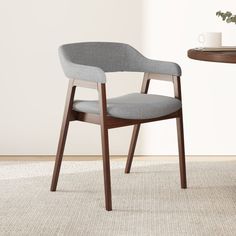 a chair sitting on top of a rug next to a wooden table with a plant in it