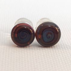 two brown glass ear plugs sitting on top of a white surface