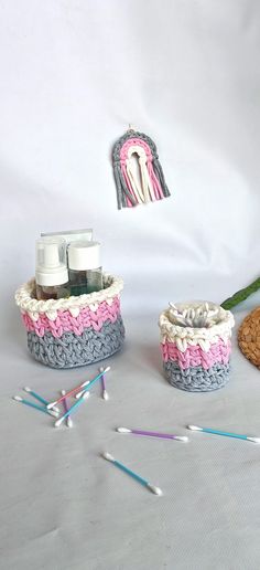 two crocheted baskets with toothbrushes and toothpaste next to them