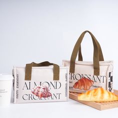 two totes bags with bread and coffee on the side next to them, one has a baguette in front of it