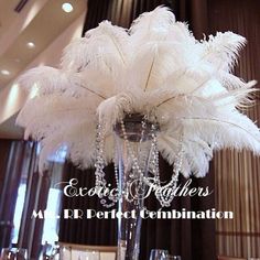 a tall vase filled with white feathers and crystal beaded beads on top of a table