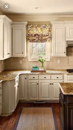 a kitchen with white cabinets and granite counter tops on a rug in front of the sink