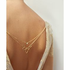 the back of a woman's shoulder wearing a gold necklace with leaves on it