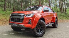 an orange truck is parked on the side of the road in front of some trees