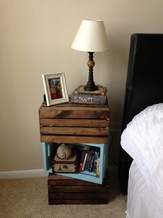 a nightstand with two books on it next to a night stand and a lamp in the corner