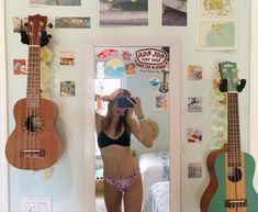 a woman taking a selfie in front of a mirror with guitars on the wall