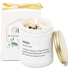 a candle in a white jar with a yellow ribbon around it and a box on the side