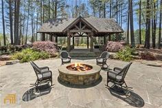 a fire pit surrounded by chairs in front of a gazebo