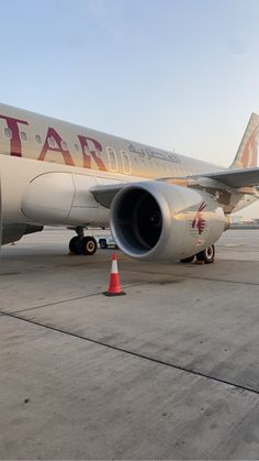 a large jetliner sitting on top of an airport tarmac next to a traffic cone