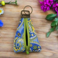 a blue and yellow zippered pouch sitting on top of a wooden table next to flowers