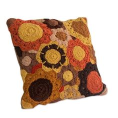 a crocheted pillow is shown on a white background with an orange, brown and yellow flower pattern