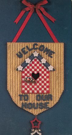 a welcome to our house sign hanging on a door hanger with a red ribbon