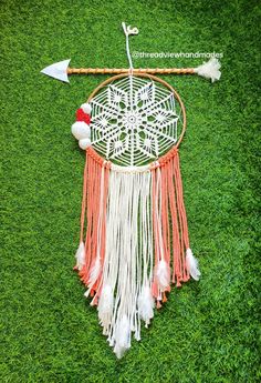 an orange and white dream catcher sitting on top of green grass